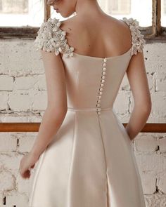 the back of a woman's wedding dress with flowers on her shoulder and shoulders