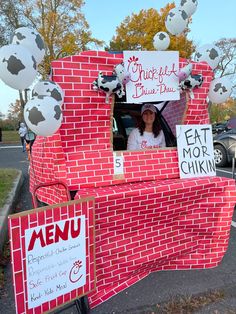 a woman sitting in the driver's seat of a truck made out of bricks