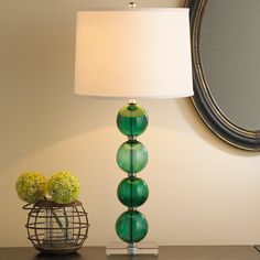 a green lamp sitting on top of a table next to a mirror