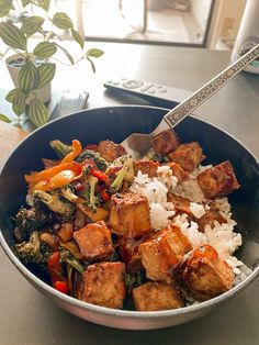 a bowl filled with tofu, broccoli and rice on top of a table