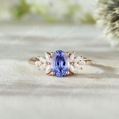 a tan gold ring with an oval blue stone surrounded by small white diamonds