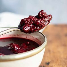 a spoon full of cranberry sauce on top of a bowl