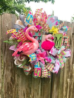 a pink flamingo wreath on top of a wooden fence