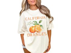 Embrace your love for nature and gardening with our vintage style "California Oranges" shirt, adorned with oranges. This short-sleeved crewneck tee is perfect for any citrus lover, farmer, plant lover, or gardener, adding a touch of cottagecore aesthetic to your wardrobe. COMFORT COLORS 1717 SHIRT: Unisex 100% US cotton - ethically grown and harvested Pre-Shrunk Fabric Relaxed Fit - Size up for a trendy oversized look Seamless Sides Double Needle Stitching Garment-dyed  CARE INSTRUCTIONS: Wash i Cottagecore Relaxed Fit Short Sleeve Tops, Orange Screen Print Tops For Spring, Relaxed Fit Cotton Top In Cottagecore Style, Cottagecore Relaxed Fit Summer Tops, Vintage Letter Print Shirt For Spring, Summer Cottagecore Relaxed Fit Tops, Cottagecore Relaxed Fit Crew Neck Tops, Spring Relaxed Fit Tops With Fruit Print, Vintage Spring Shirt With Letter Print