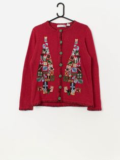 Vintage Christmas tree cardigan with appliqué present trees. This stunning red cardigan features a Christmas present tree pattern on the front, amazing gift patterned buttons, black piping and a crew neck. Made from a mid-weight wool blend. Our recommended size: Medium Label says: Medium Condition: Very good Material: 55% ramie, 15% wool, 15% acrylic, 15% nylon Measurements in inches: Pit to pit: 19 Shoulders: 15.5 Front length: 24 Back length: 25 Sleeve length: 24 Hem: 20 We recommend that you Embroidered Red Cardigan For Fall, Red Embroidered Fall Cardigan, Fitted Winter Cardigan For Festive Occasions, Fitted Cardigan For Winter Festivals, Long Sleeve Christmas Cardigan, Festive Long Sleeve Christmas Cardigan, Red Embroidered Winter Cardigan, Red Christmas Outerwear, Red Christmas Festive Outerwear