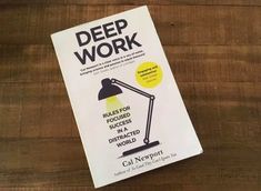 the book deep work is sitting on top of a wooden table next to a lamp