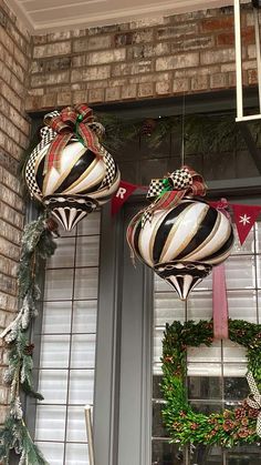 two christmas ornaments hanging from the side of a window