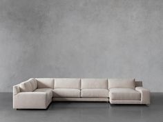 a white sectional couch sitting on top of a cement floor next to a gray wall