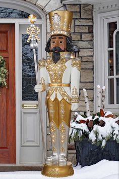 a large nutcracker statue in front of a house with snow on the ground