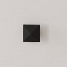 a square black object sitting on top of a white wall