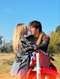 a man and woman sitting on top of a red motorcycle