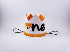 a white and orange felt crown with the word one printed on it's side