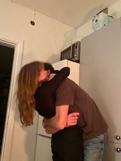 two people hugging each other in the kitchen