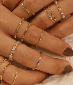 a woman's hand with five different rings on her fingers and one is holding the other