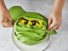 a person is decorating a cake with green icing and yellow eyes on it