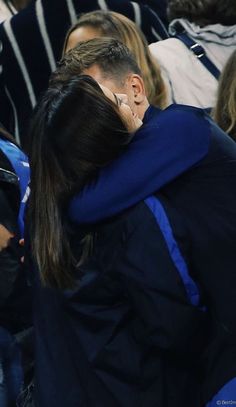 two people hugging each other in the stands