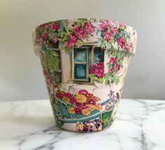 a flower pot sitting on top of a marble counter next to a window with flowers painted on it