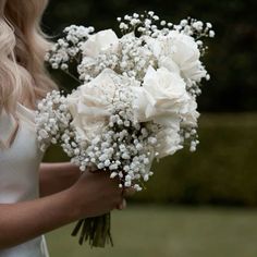 a woman holding a bouquet of white flowers