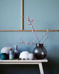 vases and jars are sitting on a table in front of a wall with blue walls