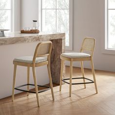 two stools sitting next to each other in front of a counter top and window