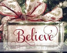 a christmas ornament with the words believe in red and white lettering on it