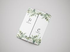 the front and back of a wedding program with watercolor leaves on it, sitting on top of a gray surface