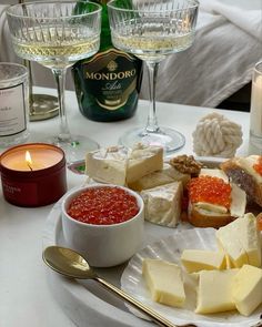 a plate full of cheese and crackers next to two wine glasses