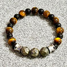 Enhance your style and spiritual well-being with our Men's Gemstone Beaded Bracelet, meticulously handmade with high-quality Tiger Eye, Black Onyx, Faceted Pyritefocal beads, and sleek stainless steel accents.  Made with 8-10 mm beads Fits an 8-8.5" wrist  This BOLDLY unique bracelet is designed for both fashion and function, offering powerful metaphysical benefits and a timeless, masculine look. Key Features: *Gemstones Used: Tiger Eye, Black Onyx, Faceted Pyrite *Accents: Stainless Steel *Hand Spiritual Obsidian Round Bead Jewelry, Spiritual Obsidian Jewelry With Round Beads, Bohemian Black Bracelets With Polished Beads, Black Bohemian Bracelet With Polished Beads, Bohemian Black Bracelet With Polished Beads, Spiritual Obsidian Beaded Jewelry, Obsidian Beaded Jewelry For Healing, Bohemian Black Stretch Bracelet With Gemstone Beads, Handmade Black Spiritual Beaded Bracelets