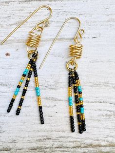 the earrings are made with black and gold seed bead, turquoise glass beads, and brass plated wire