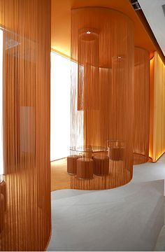 an orange room with sheer curtains hanging from the ceiling and round tables on the floor