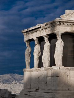 an old photo of some statues on the side of a building with clouds in the background