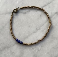 Lapis Lazuli and Faceted Brass Beaded Bracelet. Three 4 mm round lapis lazuli beads with 2-2.5 mm diamond cut faceted brass beads make up this bracelet, which closes with a lobster claw clasp. Also available in silver.I welcome custom orders! I can make this bracelet with other semi precious stones and silver or brass beads. The third photo shows other bracket options that are currently available.Arrives in a gift box. Hand-strung Brass Bracelets With Round Beads, Brass Beaded Bracelets With Round Beads, Brass Bracelets With Round Gold Beads, Gold Lapis Lazuli Beaded Bracelets With Round Beads, Gold Beaded Lapis Lazuli Bracelets, Adjustable Lapis Lazuli Beaded Bracelet With Faceted Beads, Bracelets Hippie, Silver Beaded Bracelet, Hippie Bracelets