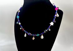 This quirky handmade necklace combines iridescent seed beads, and various other beads in shades like neon pink, turquouse, raspberry red, lavender purple, and royal blue to create a unique piece. This necklace isn't for the faint of heart, but those who like to stand out, and add a little off-beat color to their look. Oblong pearl charms in different shapes hang from the necklace, as well as other pearl and crystal beads, adding other intriguing bits to the necklace. Necklace is secured in the back with a lobster clasp hook, but can be adjusted fora looser fit. Red Lavender, Crystal Bead Necklace, Raspberry Red, Pink Star, Necklace Necklace, Pink Stars, Pearl Charms, Lavender Purple, Beaded Choker