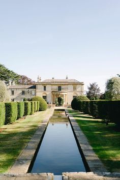 a large house sitting on top of a lush green field next to a small pond