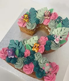 a cake shaped to look like the letter e is decorated with flowers and teddy bears