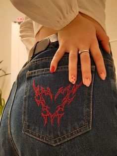 a woman's hand on the back of her jean pants with red dragon tattoos