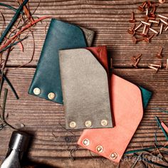 three leather wallets sitting on top of a wooden table