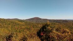 the mountains are covered with trees and bushes on a sunny day in autumn or fall