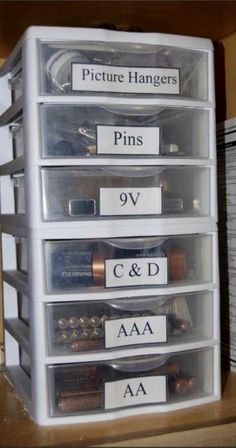 the drawers are labeled with pictures, pins, and cd's in clear plastic bins