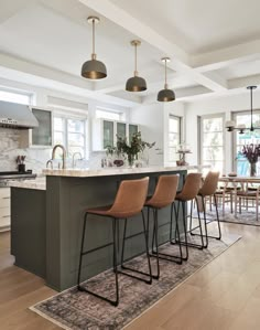 a kitchen with an island and bar stools in front of the countertop area