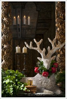 a deer head with flowers and candles in the background