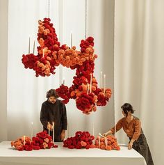 two people standing in front of a table with flowers and candles on top of it