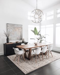 a dining room table with white chairs and a rug on the floor in front of it