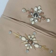 two gold and white brooches are laying next to each other on a bed