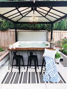 an outdoor hot tub with four stools and a table in the middle of it