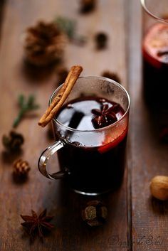 two glasses of mulled with cinnamon and anisette on a wooden table next to pine cones