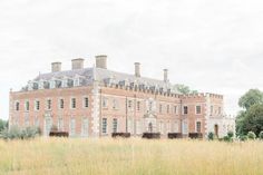 an old brick building in the middle of a field with tall grass and trees around it