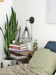 a bedroom with a bed, plant and books on the shelf next to the bed