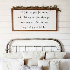 a bed with white sheets and pillows in front of a wooden sign that says, there is