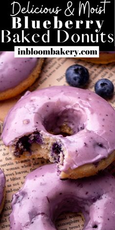 blueberry donuts with purple icing and fresh blueberries are on top of an old book